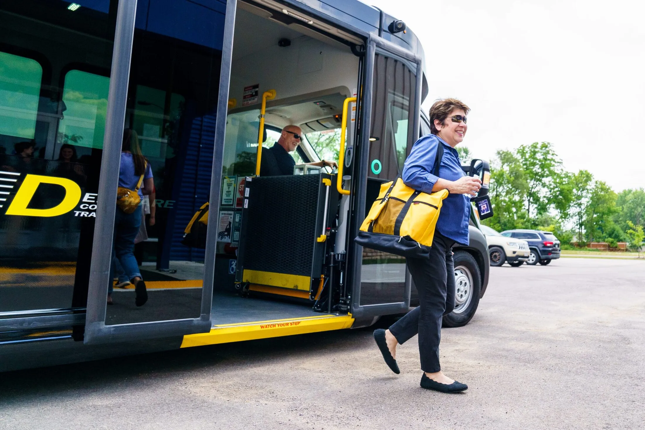A rider with a yellow tote steps off a DCT van