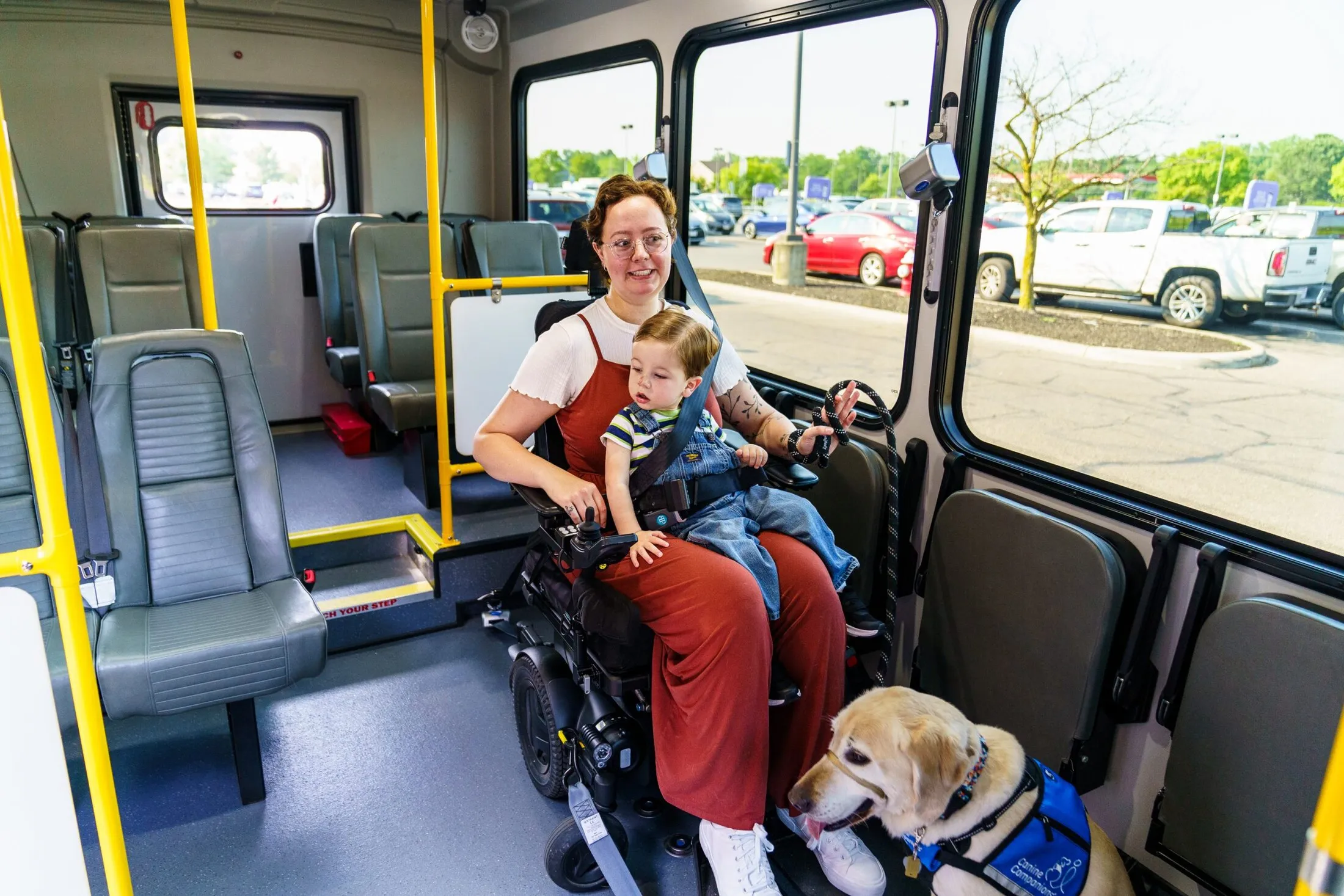 A rider in a wheelchair with a child and a service dog on board